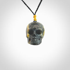 This picture shows a large sized Bumblebee Jasper stone skull pendant that we have hand carved. It is polished to a soft shine and is a very striking piece. The cord is a black colour and has a small yellow floret binding just above the pendant.