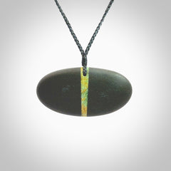 A drop pendant made from Onewa Stone - New Zealand Greywacke - with a fine Pounamu insert spliced into the middle. Hand carved stone drop with New Zealand Jade centre. Provided with an adjustable charcoal grey cord and packaged in a woven kete pouch.