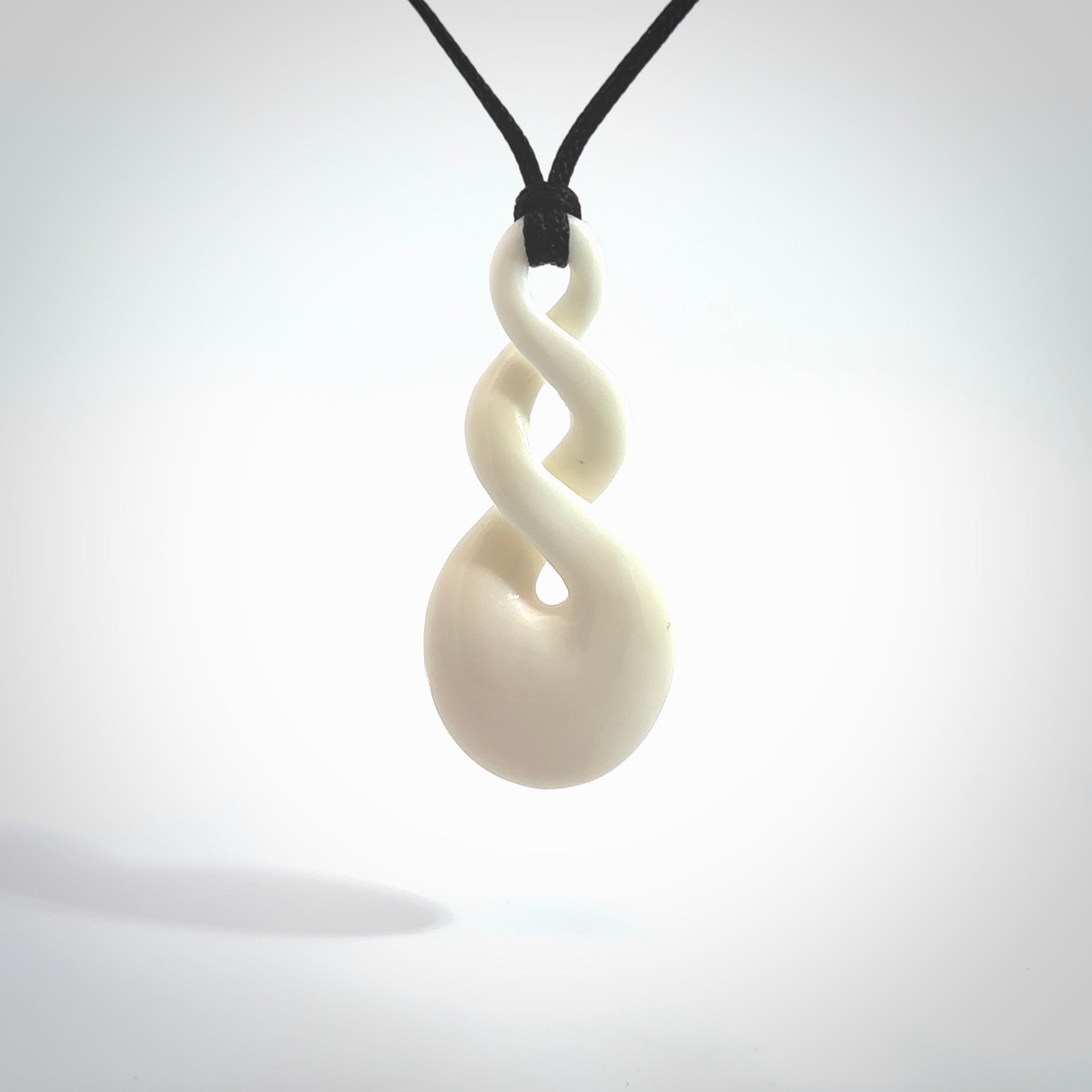 These are very cool, simple double twist pendants carved from natural bone. We have bound these in a black cord and will ship them to you wherever you are. Hand carved by NZ Pacific.