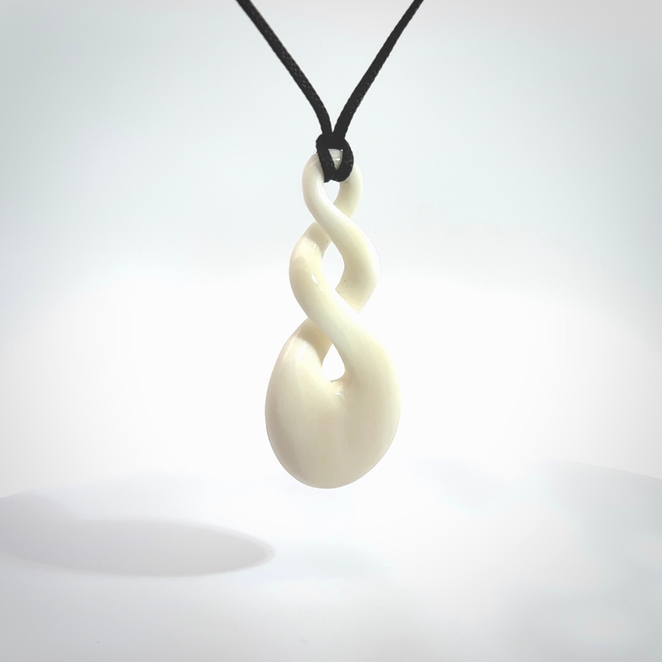 These are very cool, simple double twist pendants carved from natural bone. We have bound these in a black cord and will ship them to you wherever you are. Hand carved by NZ Pacific.