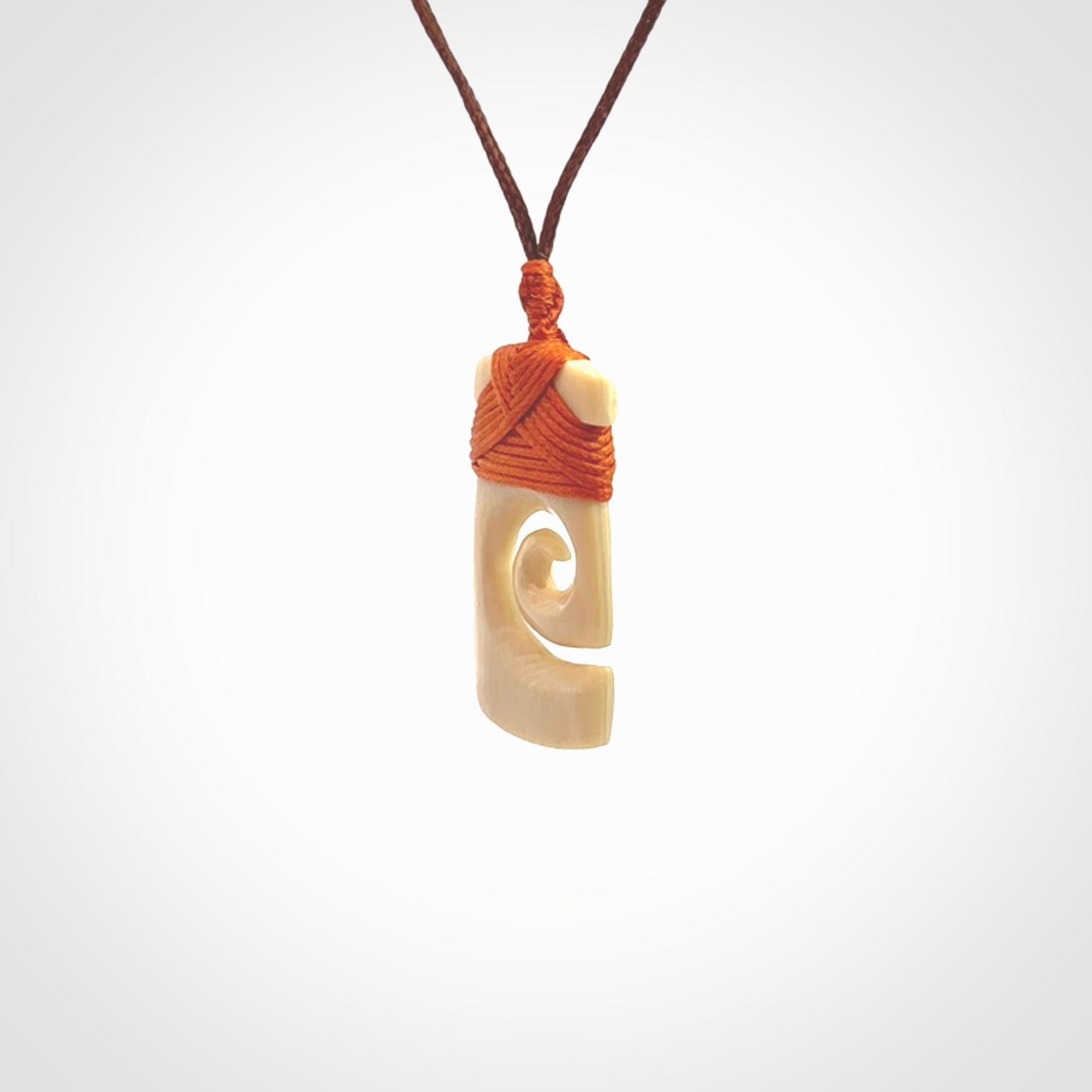 Hand carved Woolly Mammoth Tusk toki with koru pendant. Toki with koru necklace carved from ancient woolly mammoth tusk. Provided with adjustable cord and packaged in a woven kete pouch.