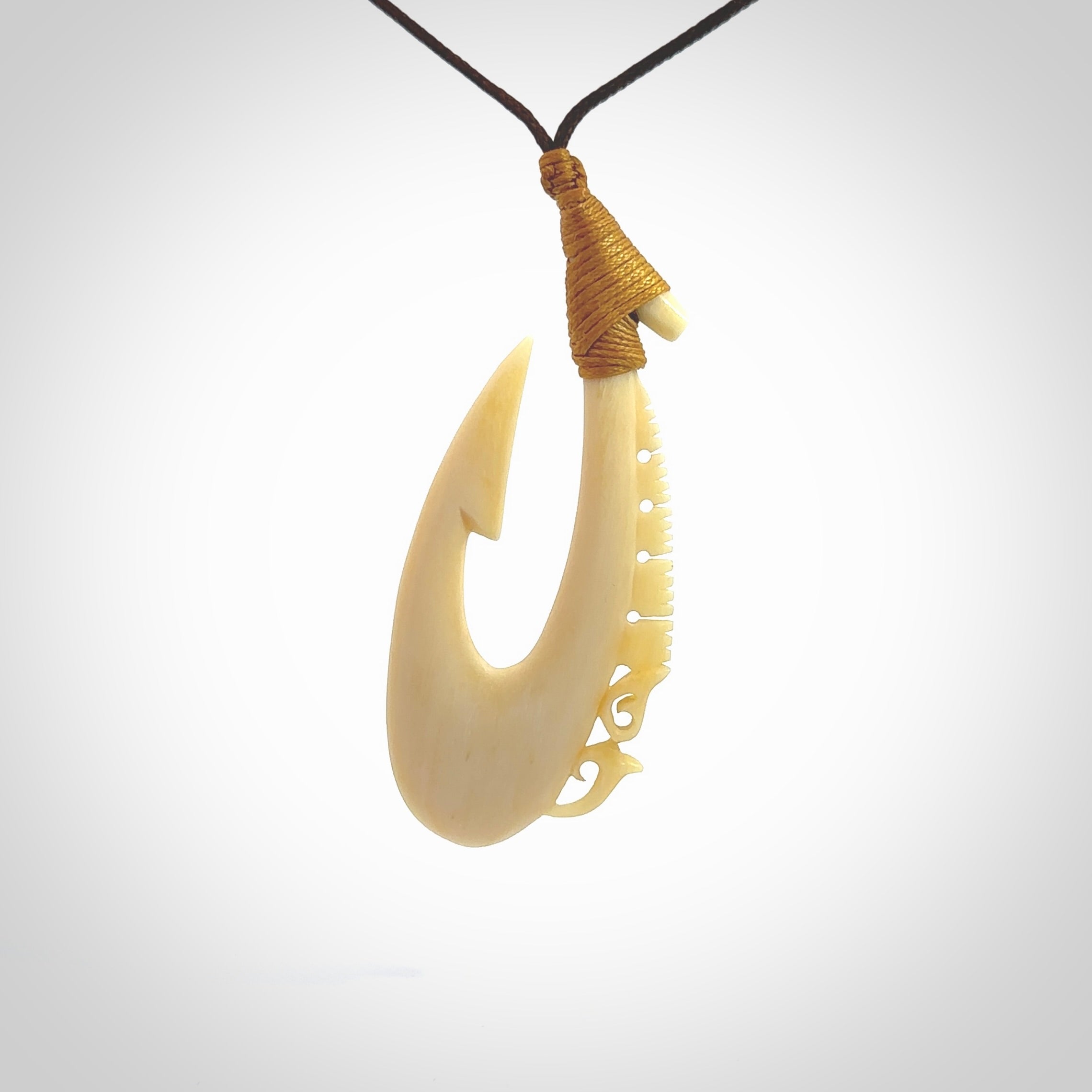 Natural cow bone hook with Manaia pendant. Hand carved by Yuri Terenyi in New Zealand. Maori design pendant for sale online. Natural bone manaia, hook necklace with adjustable cord. Free delivery worldwide.