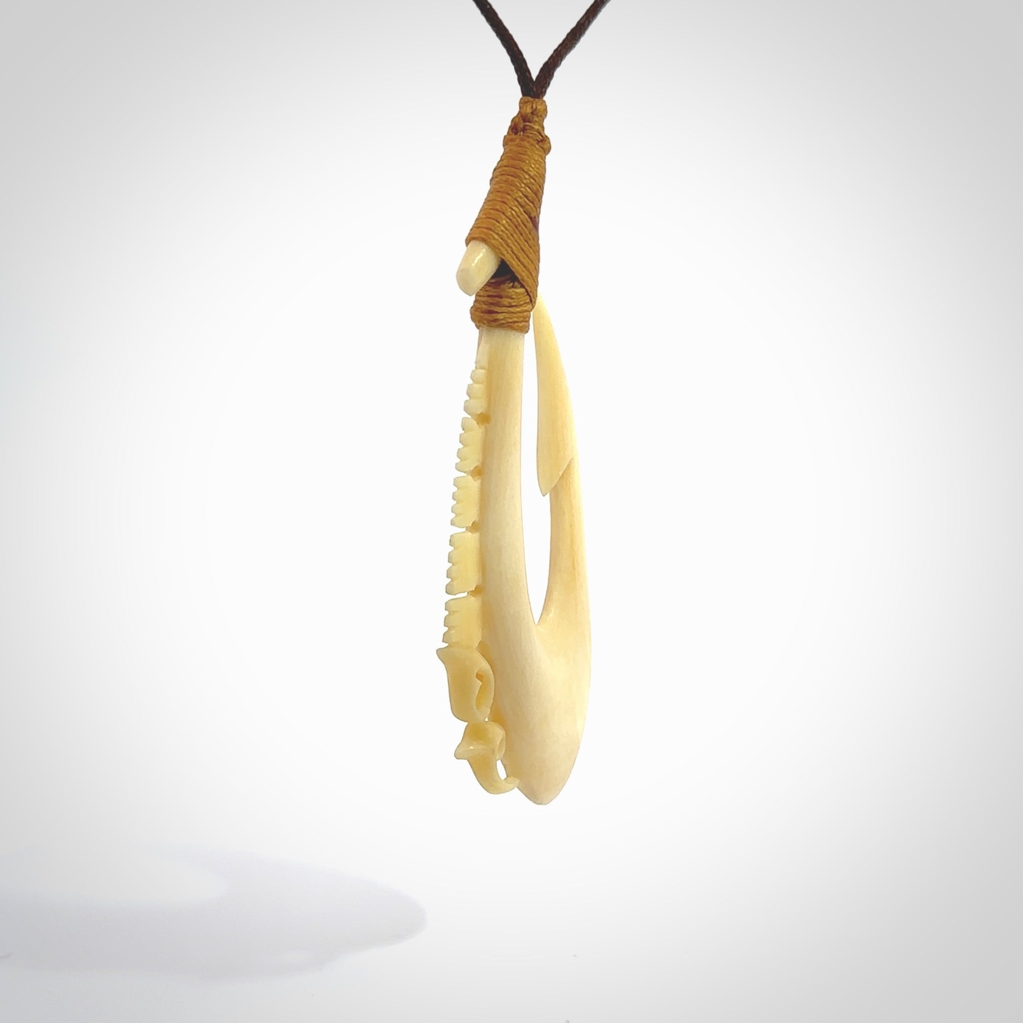 Natural cow bone hook with Manaia pendant. Hand carved by Yuri Terenyi in New Zealand. Maori design pendant for sale online. Natural bone manaia, hook necklace with adjustable cord. Free delivery worldwide.