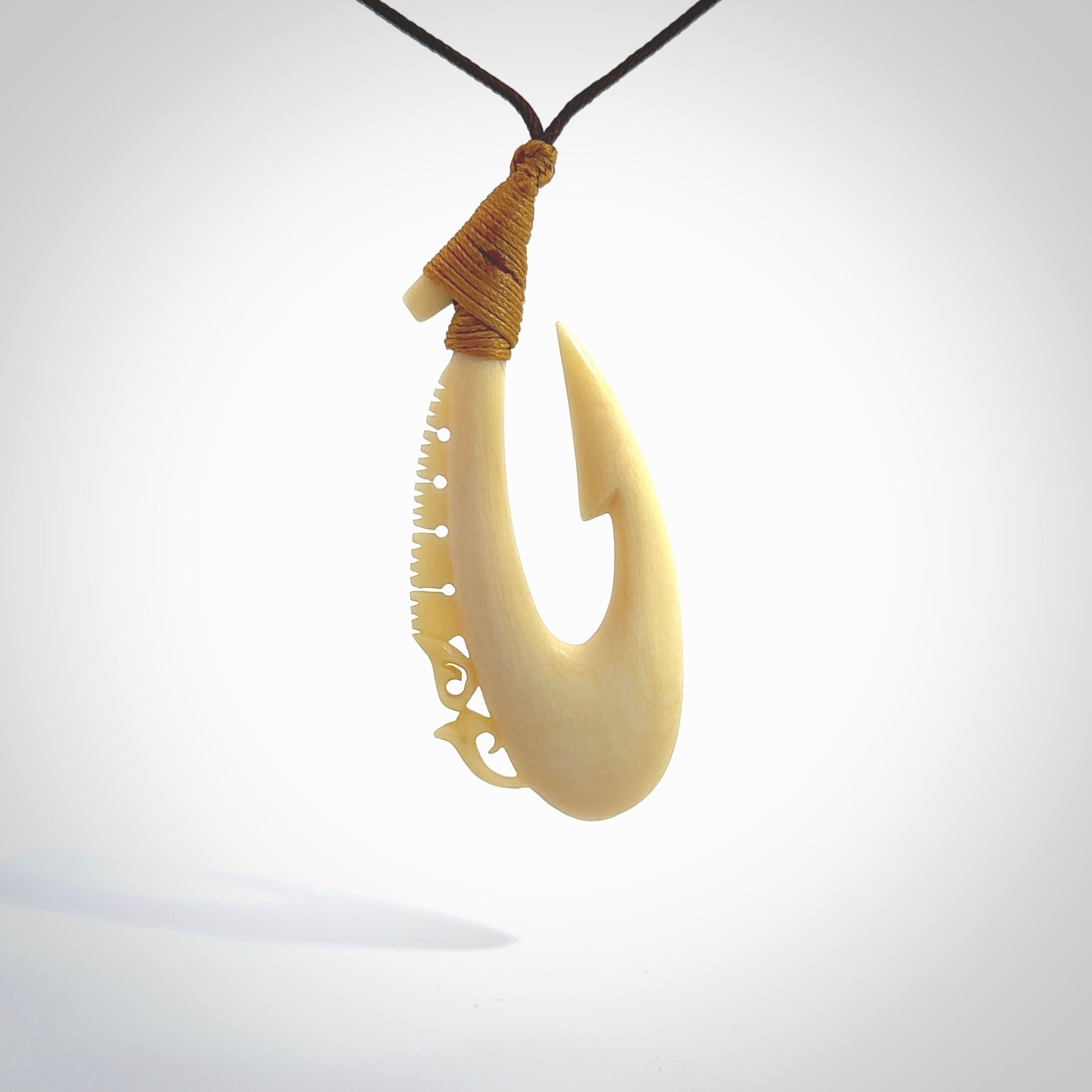 Natural cow bone hook with Manaia pendant. Hand carved by Yuri Terenyi in New Zealand. Maori design pendant for sale online. Natural bone manaia, hook necklace with adjustable cord. Free delivery worldwide.