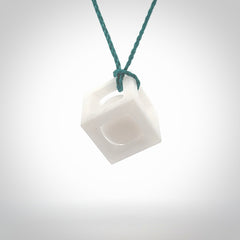 A hand carved medium sized white nephrite Jade square box with ball inside necklace. The cord is blue and adjustable in length. A medium sized hand made cube/box with ball necklace in white nephrite Jade stone. One off work of art to wear.