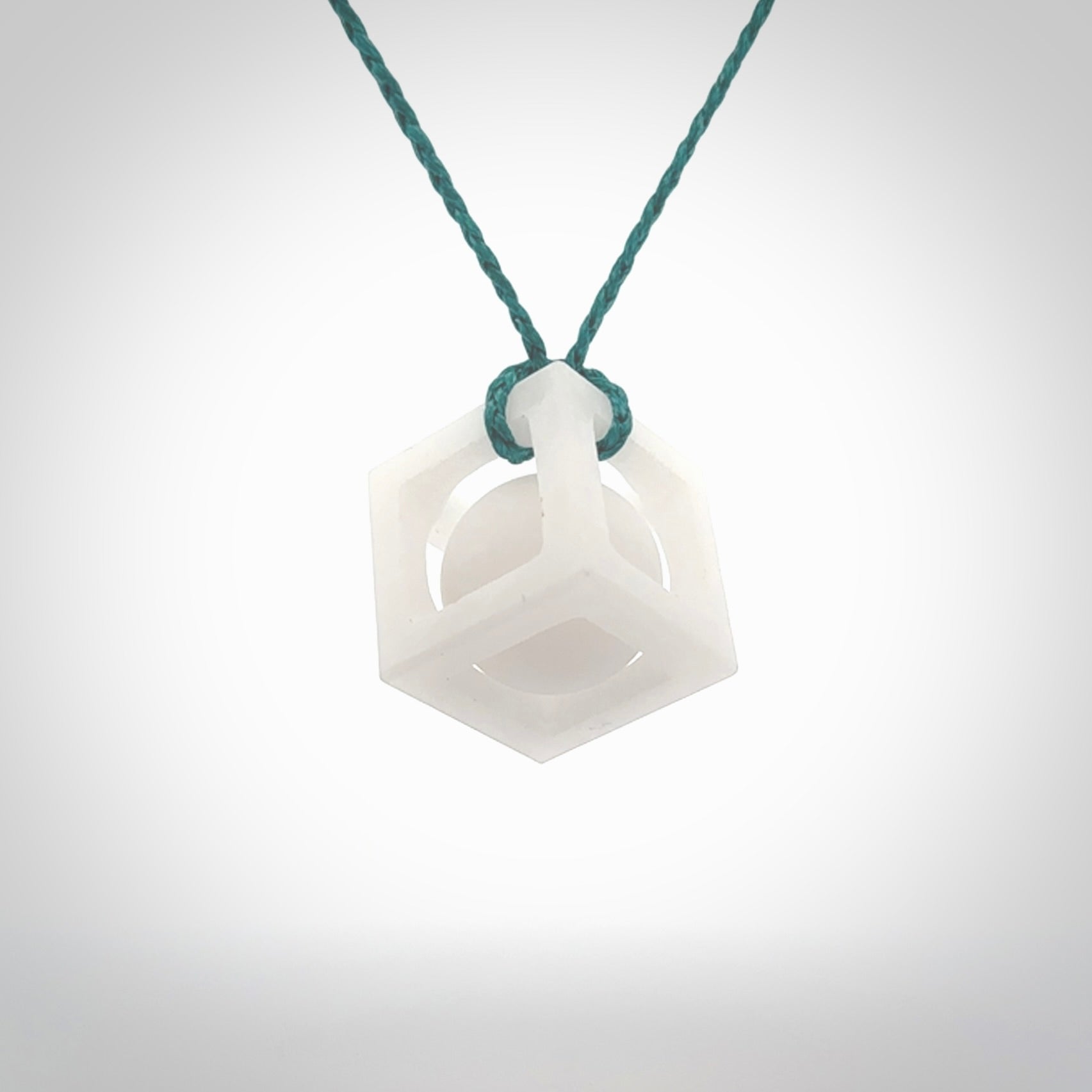 A hand carved medium sized white nephrite Jade square box with ball inside necklace. The cord is blue and adjustable in length. A medium sized hand made cube/box with ball necklace in white nephrite Jade stone. One off work of art to wear.