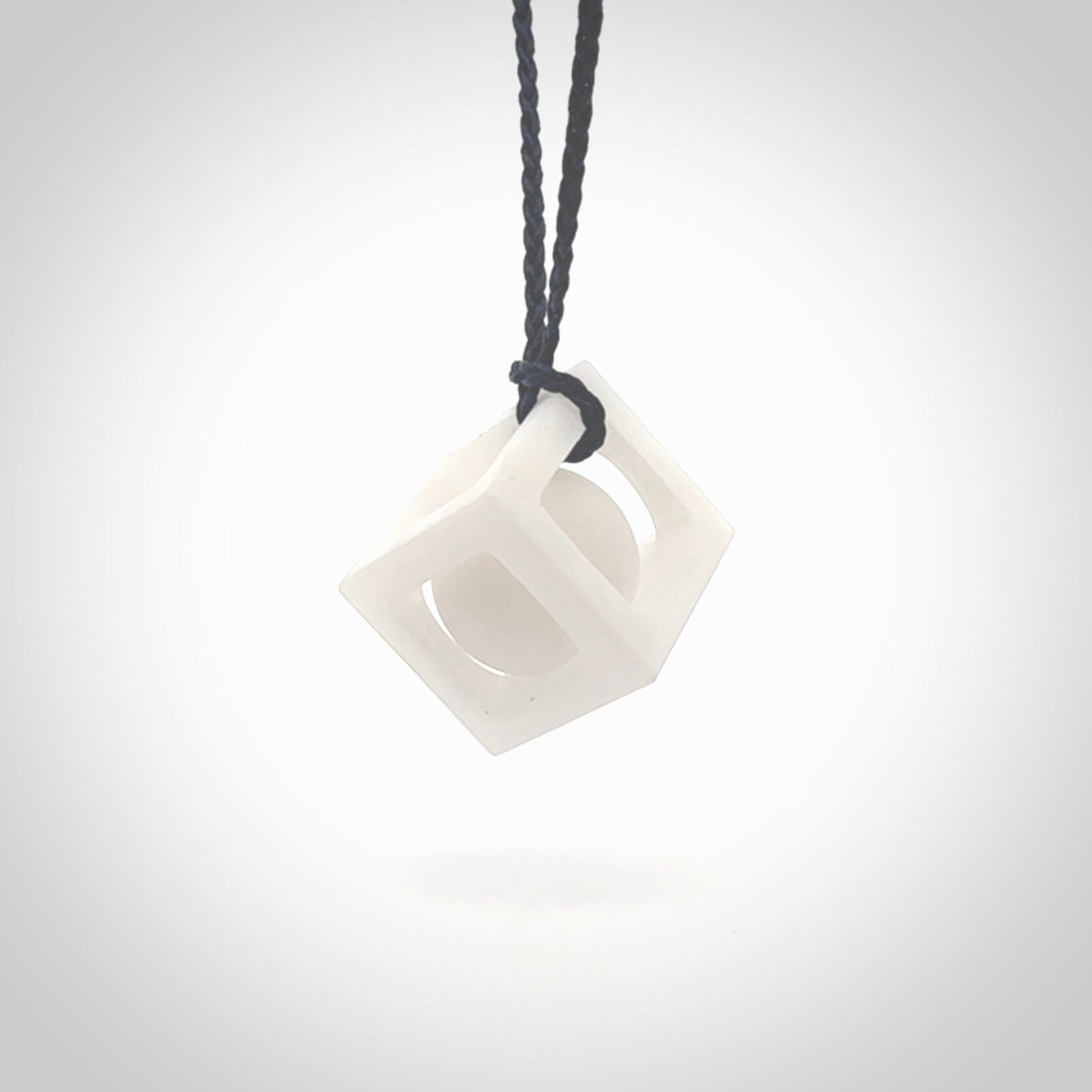 A hand carved medium sized white nephrite Jade square box with ball inside necklace. The cord is blue and adjustable in length. A medium sized hand made cube/box with ball necklace in white nephrite Jade stone. One off work of art to wear.