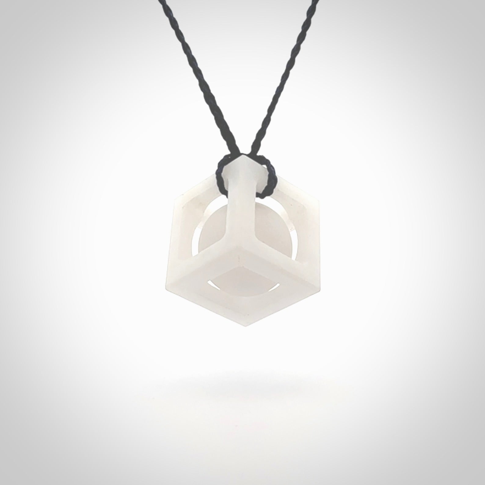 A hand carved medium sized white nephrite Jade square box with ball inside necklace. The cord is blue and adjustable in length. A medium sized hand made cube/box with ball necklace in white nephrite Jade stone. One off work of art to wear.