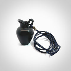 This picture shows a vase pendant that we designed in black jade. It is a black vase necklace that is carved in detail. A really attractive and eye-catching piece of handmade jewellery. The cord is hand plaited braid in charcoal grey and maui blue and the length can be adjusted. Delivered to you in a woven kete pouch and shipped with Express Courier.