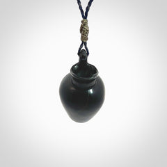 This picture shows a vase pendant that we designed in black jade. It is a black vase necklace that is carved in detail. A really attractive and eye-catching piece of handmade jewellery. The cord is hand plaited braid in charcoal grey and maui blue and the length can be adjusted. Delivered to you in a woven kete pouch and shipped with Express Courier.