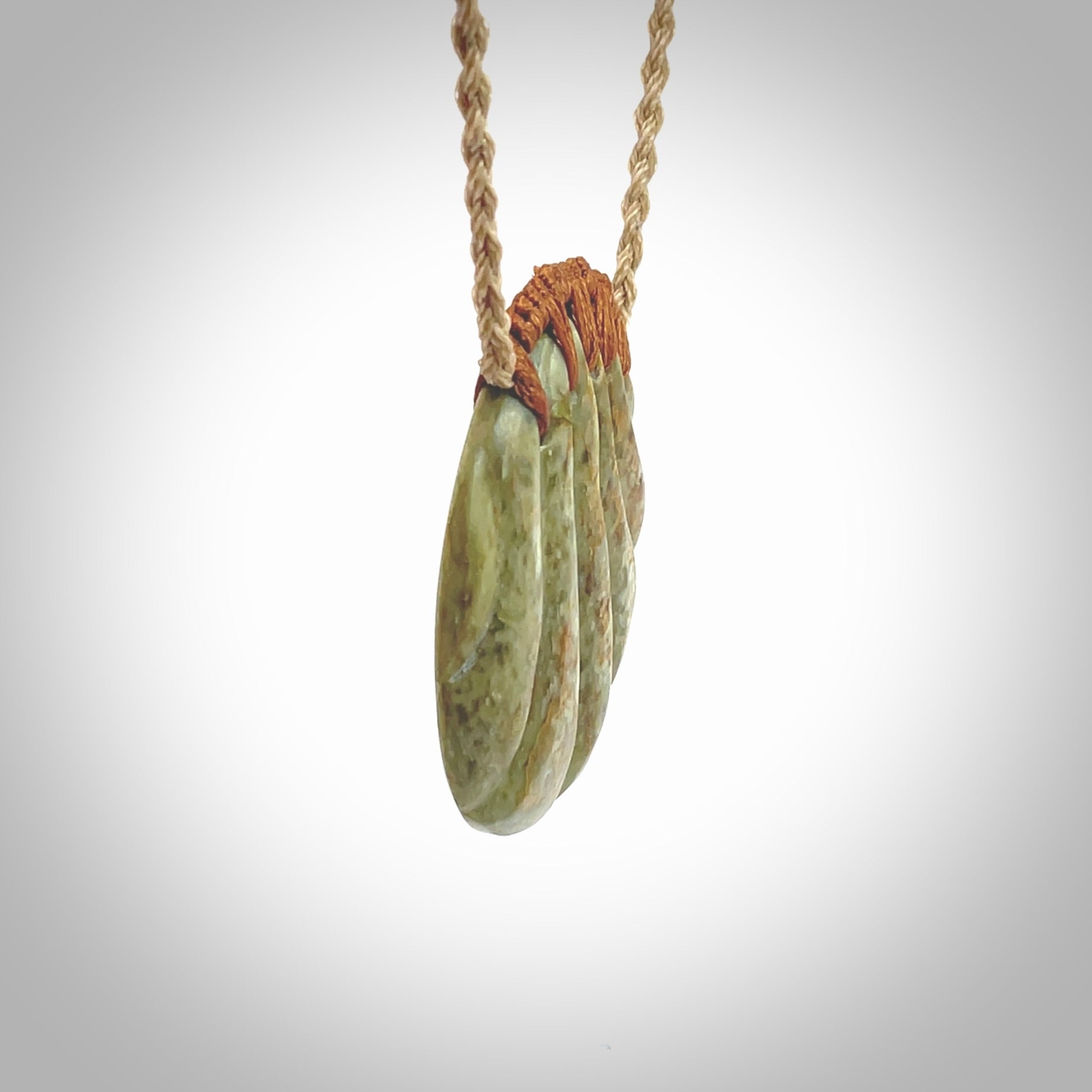 This picture shows a hand carved sea shell disc pendant made from a flowering green/orange coloured flower jade. Hand made by Ana Krakosky. It is provided with an adjustable 4-Plait Kalahari tan cord and chestnut brown binding. Delivered to you with Express Courier.