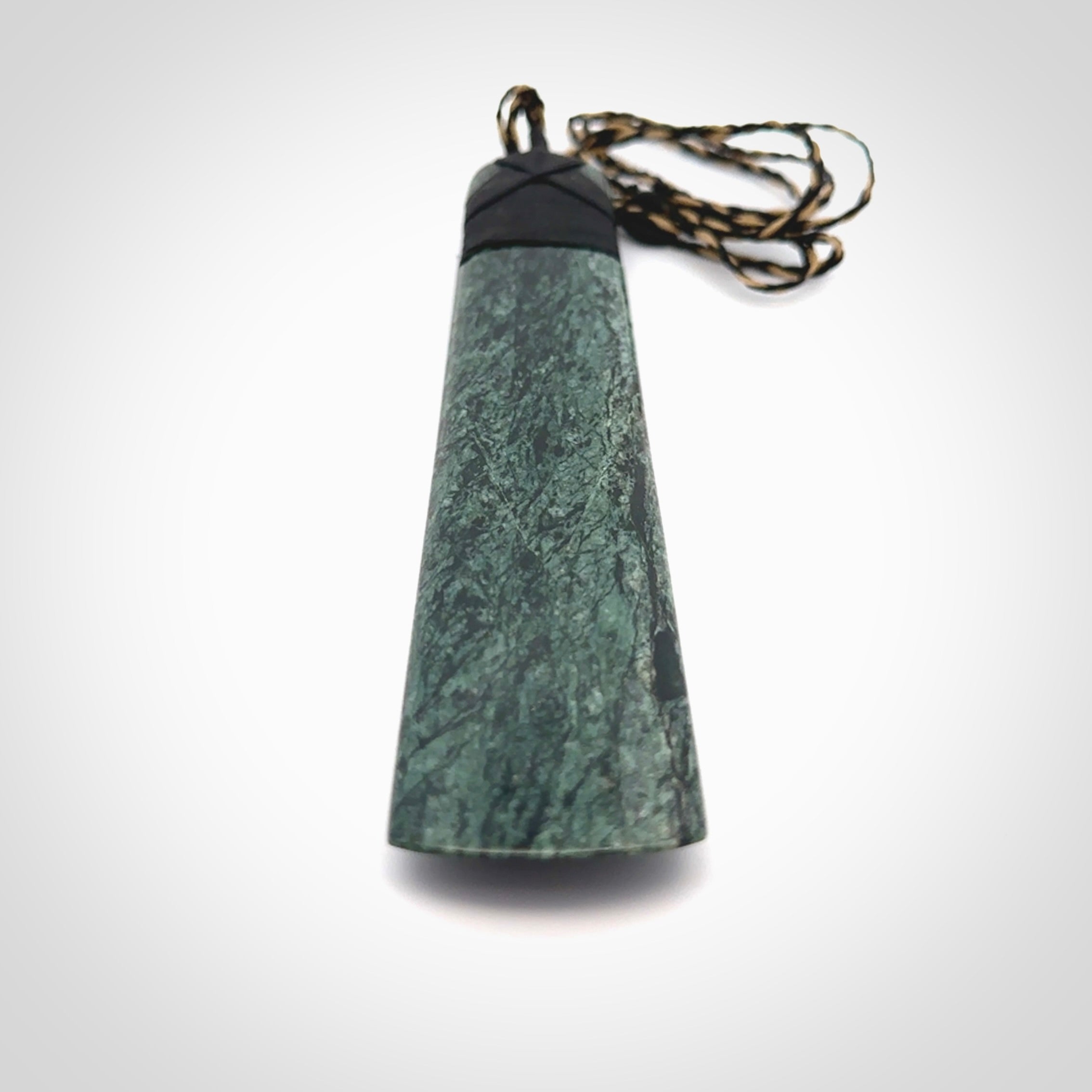 Large New Zealand Tangiwai Pounamu Toki pendant with Tangiwai boulder display case. Hand carved from a lovely piece of local New Zealand Tangiwai Stone. The quality of the workmanship and design is outstanding - this is a piece you will want to wear all the time. We have suspended this from an adjustable 3-plait tan/black cord.