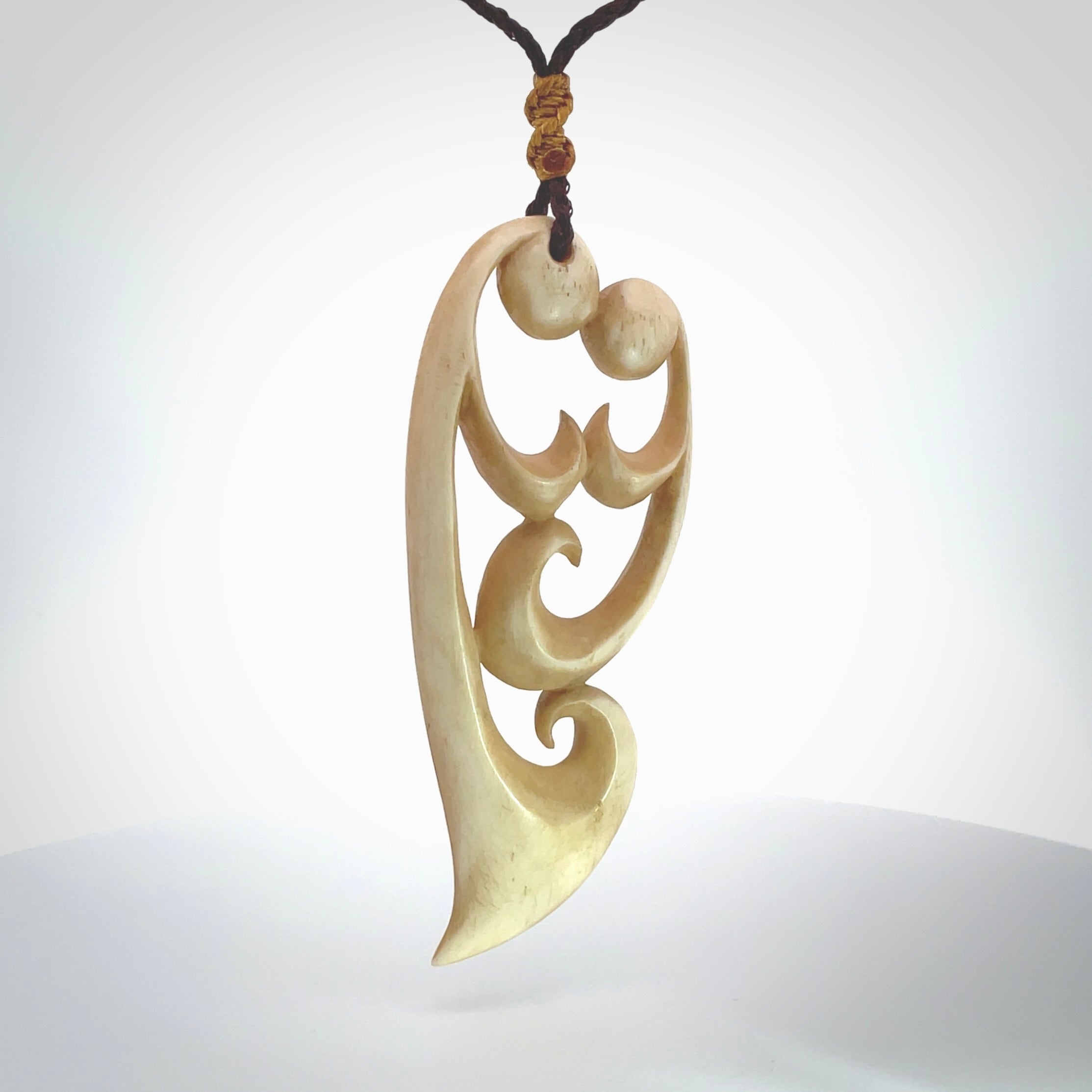 A hand carved masterpiece. A beautiful, large, contemporary pendant carved from bone by Yuri Terenyi for NZ Pacific. This is a true piece of wearable art which is collectible. A one-off pendant representing a mother and child. Provided with an adjustable chocolate brown cord and packaged in a woven kete pouch.