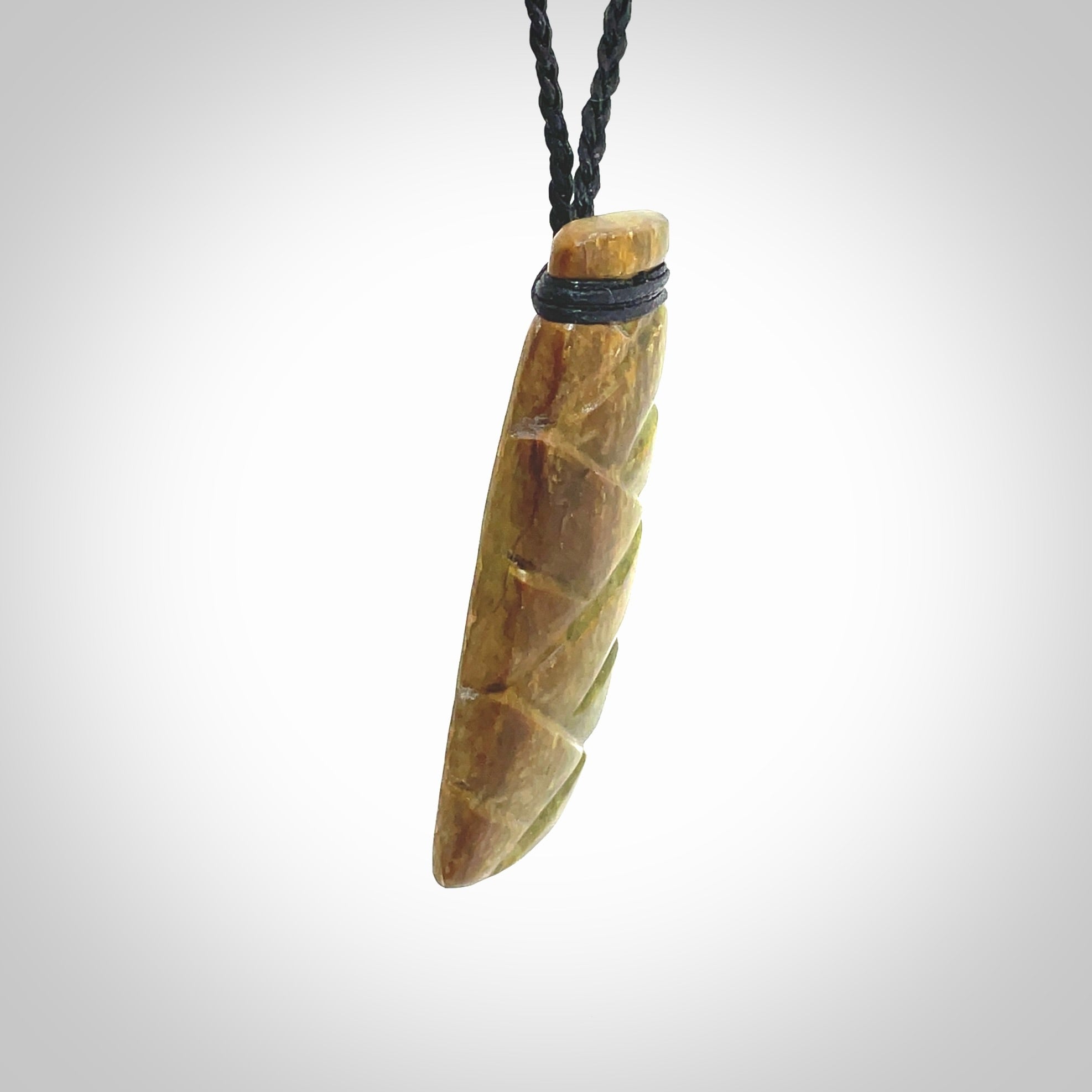 This picture shows a toki pendant carved with a woven front face and a flat back. It is made from a piece of rare New Zealand Flower Jade by our artist and carver Ana Krakosky. The cord is black and is length adjustable.