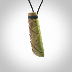 This picture shows a toki pendant carved with a woven front face and a flat back. It is made from a piece of rare New Zealand Flower Jade by our artist and carver Ana Krakosky. The cord is black and is length adjustable.