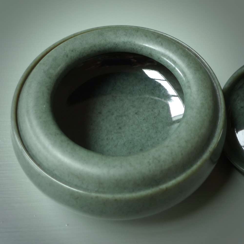 This photo shows a hand carved, Wyoming 'Sage' Nephrite Jade bowl sculpture. This 3.5 inch bowl carved from extremely fine-grained Sage. With Wyoming Black Jade and Sterling Silver, high domed centre grip. This hand crafted work of art was hand made by award winning New Zealand carver Donn Salt.