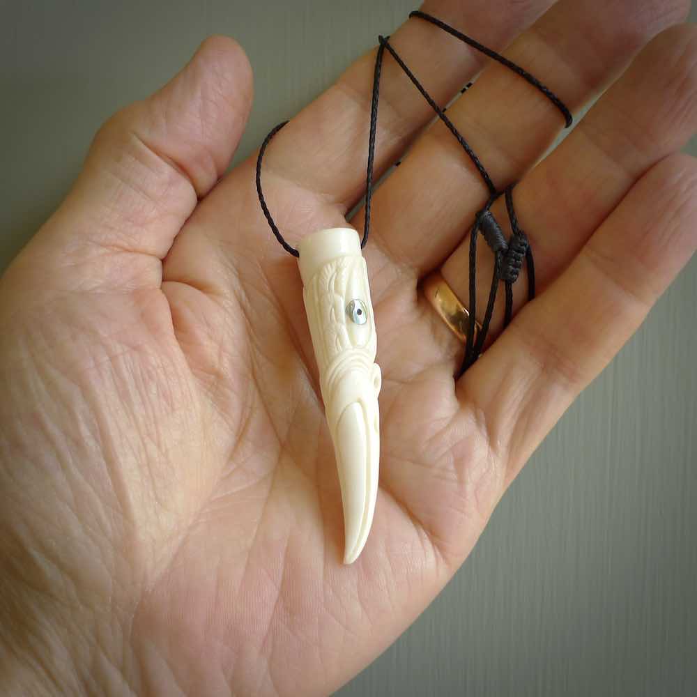 A mythical bird head hand carved from bone with Paua shell eyes. This is a one only bird head with long beak necklace hand made from natural bone with paua shell eyes. This bird head has engravings and is a magnificent piece of art to wear. It is delivered on a black adjustable cord.