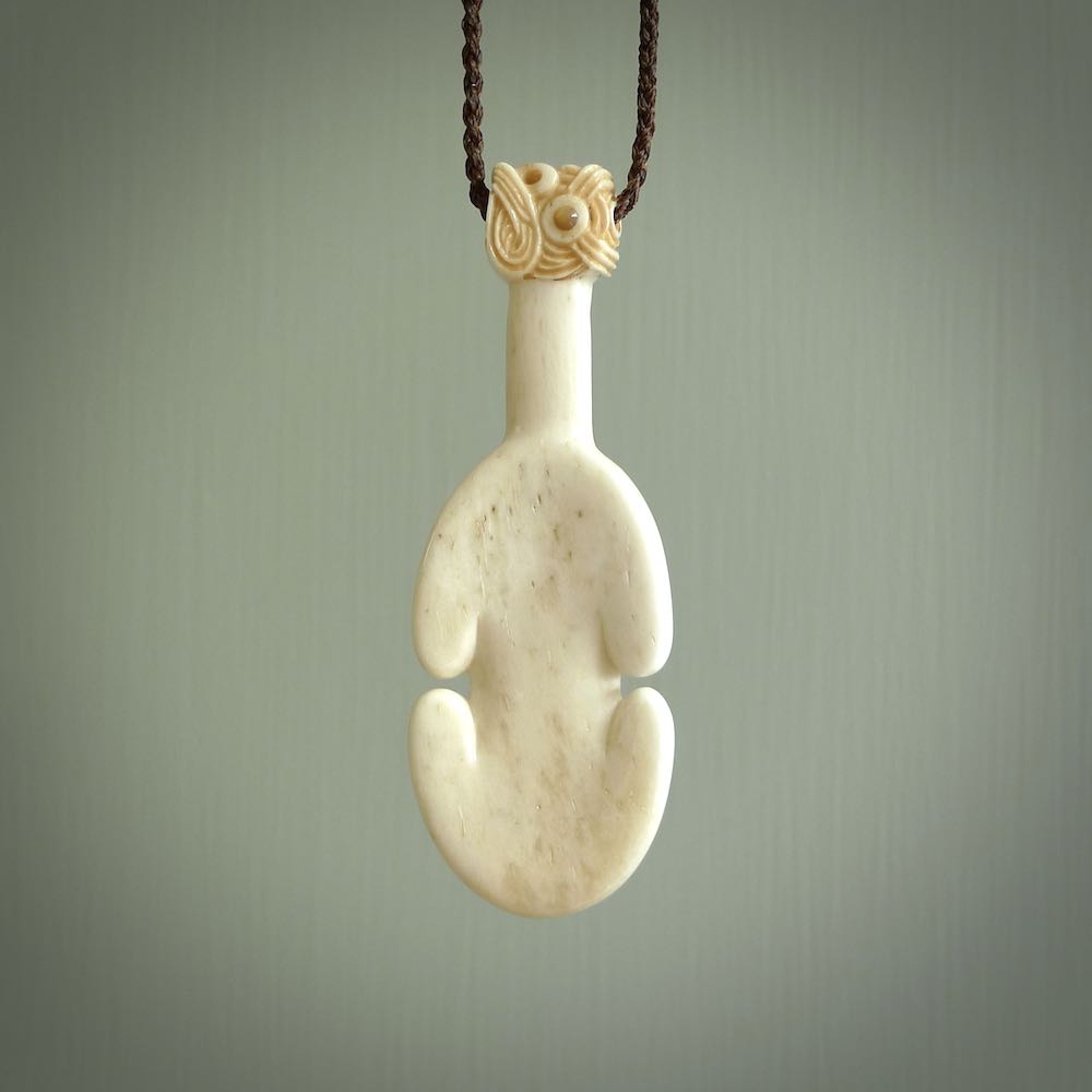 Hand carved engraved bone patu necklace hand made here in New Zealand. One only artistic patu pendant with hand plaited dark brown adjustable cord. Shipped to you with Express Courier. Stand out patu pendant for men and women. Bone patu with Paua shell insert eyes.