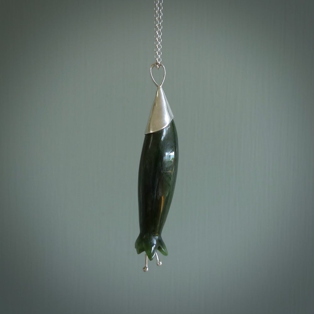 A photo of a harakeke, or flax flower, carved from a colourful piece of New Zealand flower jade. The cap and stamens are made from Sterling Silver and the cord is an Olive braid which is length adjustable.