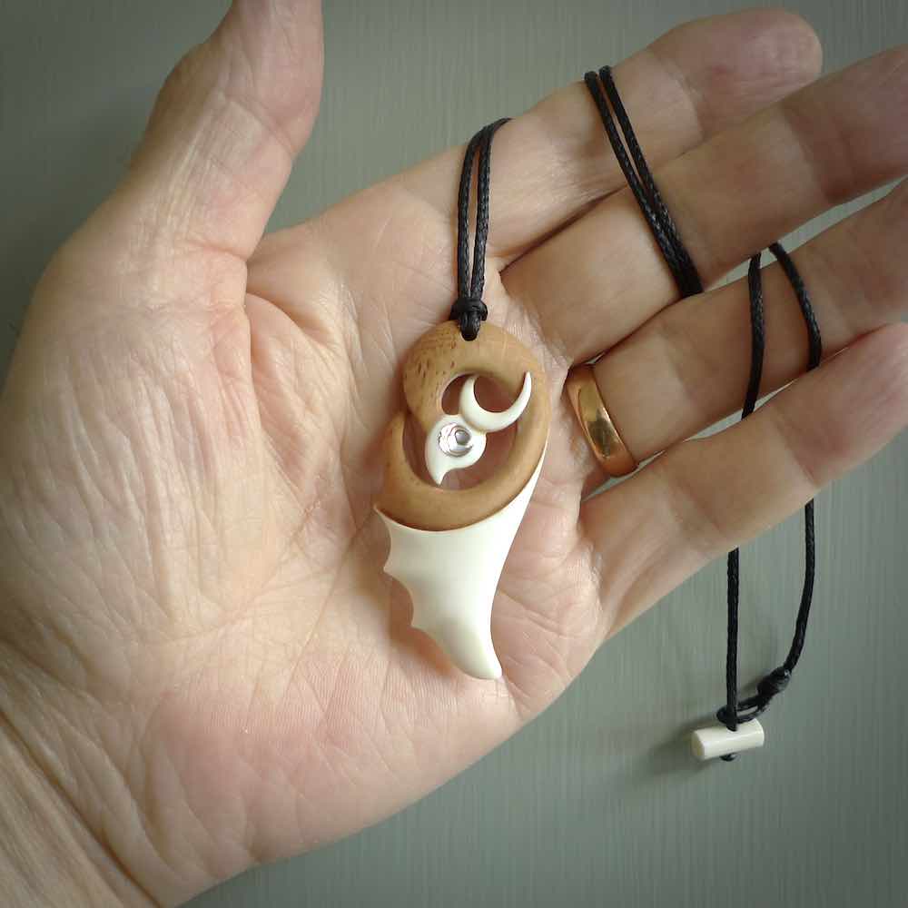 A hand carved bone contemporary bird pendant. The cord is a black colour and is a fixed length. A medium sized hand made contemporary necklace by New Zealand artist Kerry Thompson. Kerry has stained parts of the bone which really add to the dimension of this pendant. One off work of art to wear.