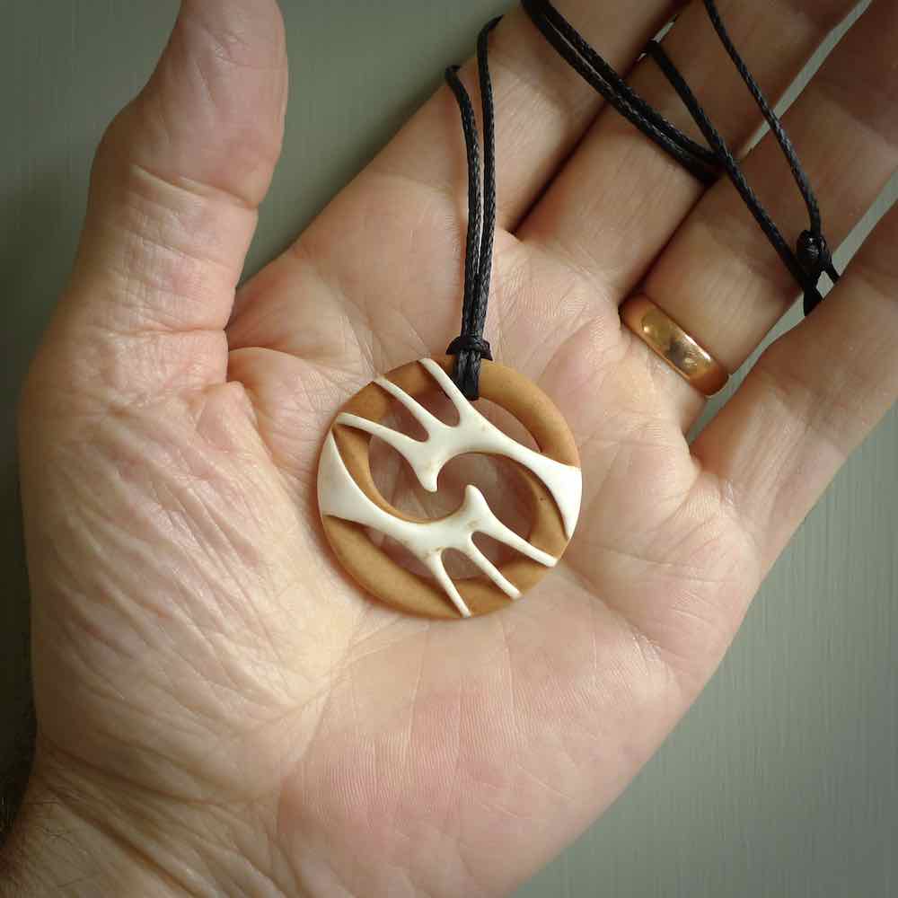 A hand carved bone contemporary, intricate pendant. The cord is a black colour and is a fixed length. A medium sized hand made contemporary necklace by New Zealand artist Kerry Thompson. Kerry has stained parts of the bone which really add to the dimension of this pendant. One off work of art to wear.