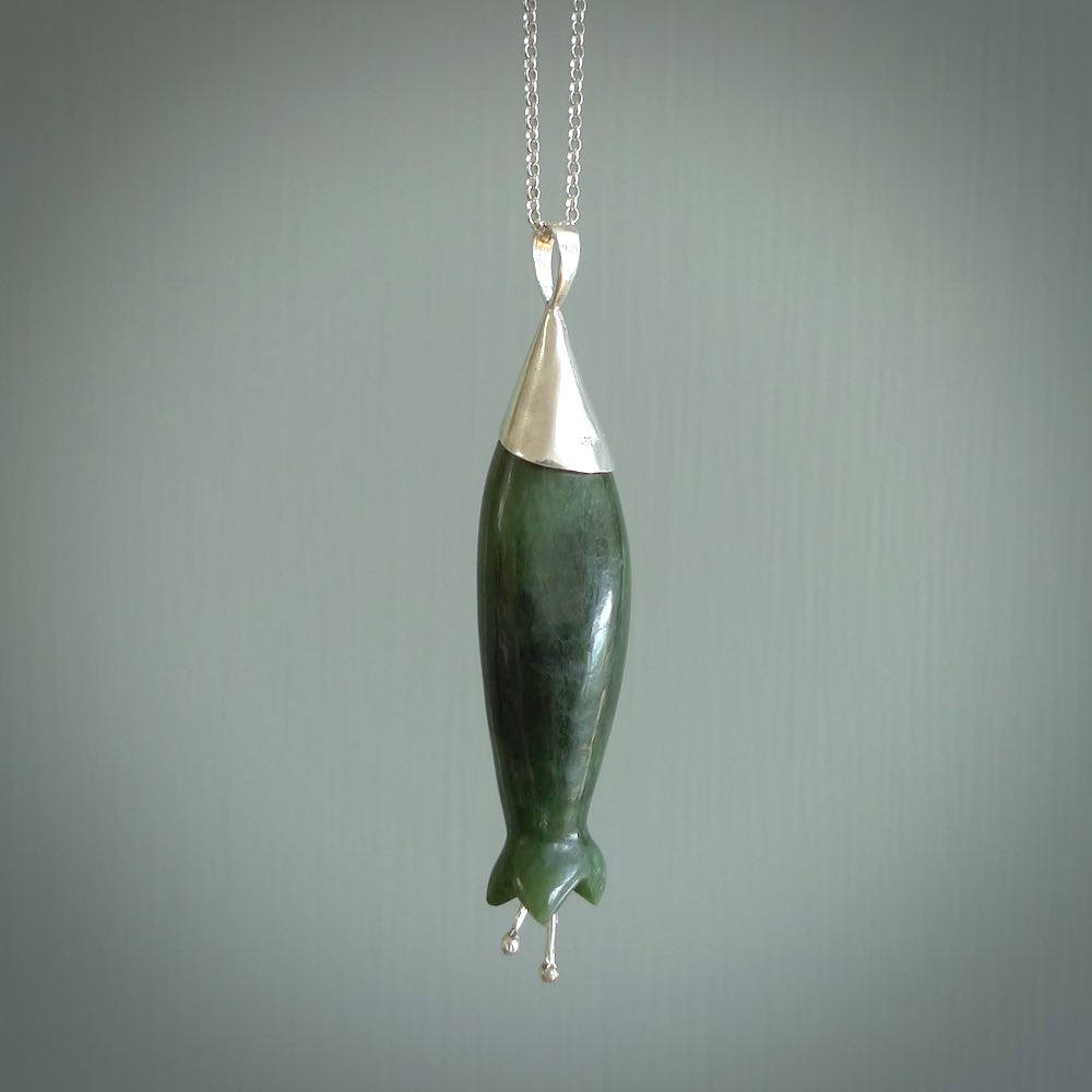 A photo of a harakeke, or flax flower, carved from a colourful piece of New Zealand flower jade. The cap and stamens are made from Sterling Silver and the cord is an Olive braid which is length adjustable.