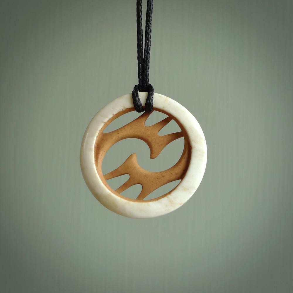 A hand carved bone contemporary, intricate pendant. The cord is a black colour and is a fixed length. A medium sized hand made contemporary necklace by New Zealand artist Kerry Thompson. Kerry has stained parts of the bone which really add to the dimension of this pendant. One off work of art to wear.