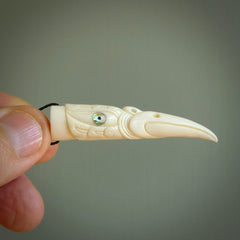 A mythical bird head hand carved from bone with Paua shell eyes. This is a one only bird head with long beak necklace hand made from natural bone with paua shell eyes. This bird head has engravings and is a magnificent piece of art to wear. It is delivered on a black adjustable cord.