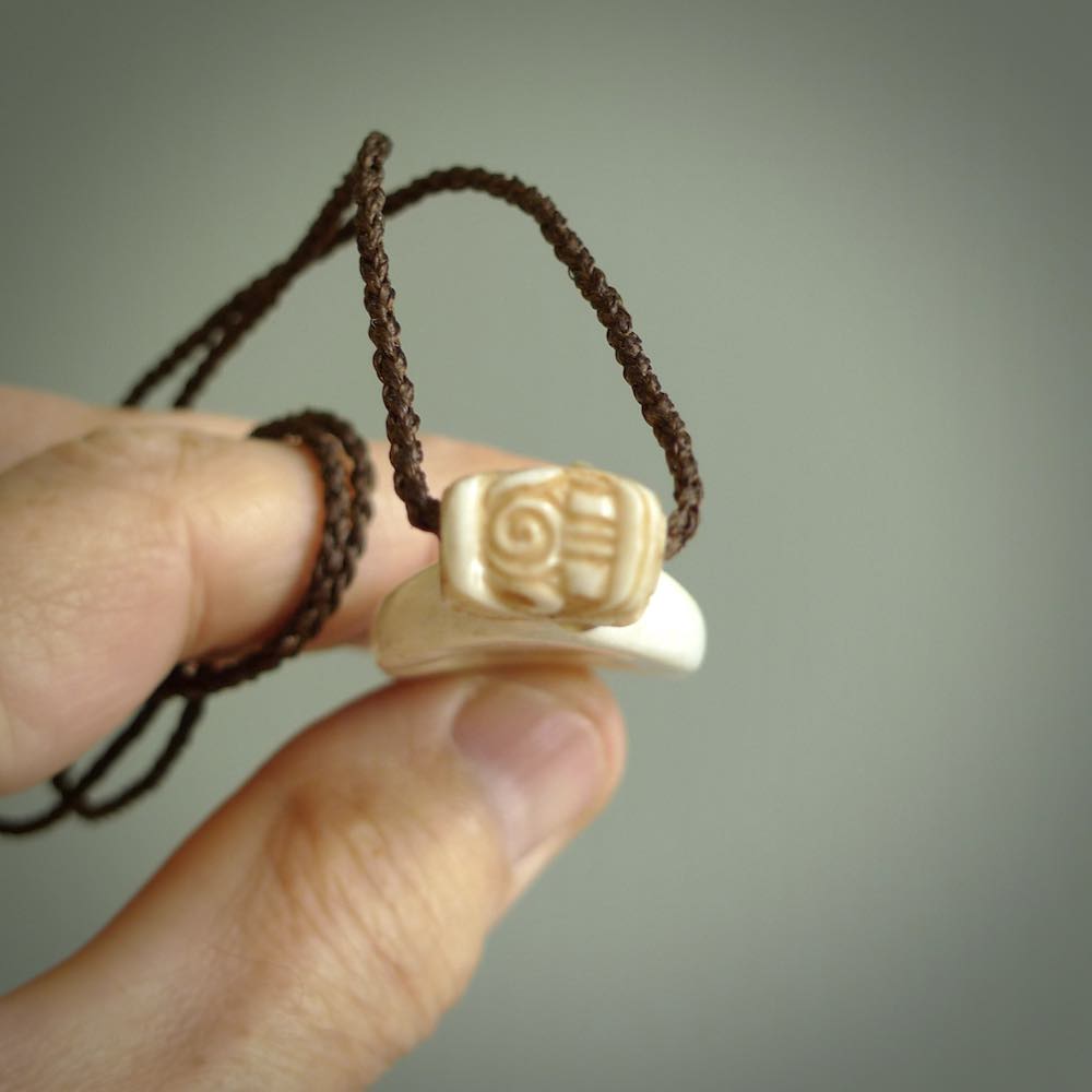 Hand carved engraved bone patu necklace hand made here in New Zealand. One only artistic patu pendant with hand plaited dark brown adjustable cord. Shipped to you with Express Courier. Stand out patu pendant for men and women. Bone patu with Paua shell insert eyes.