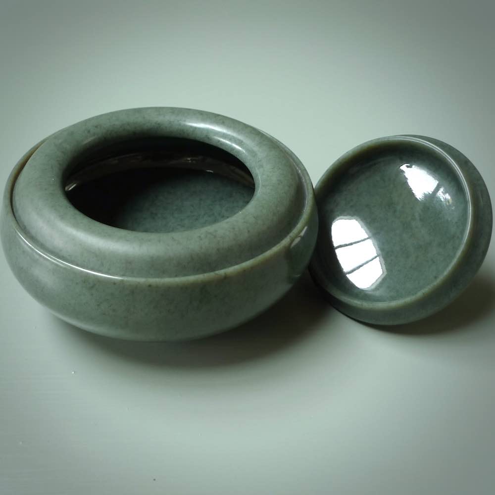 This photo shows a hand carved, Wyoming 'Sage' Nephrite Jade bowl sculpture. This 3.5 inch bowl carved from extremely fine-grained Sage. With Wyoming Black Jade and Sterling Silver, high domed centre grip. This hand crafted work of art was hand made by award winning New Zealand carver Donn Salt.