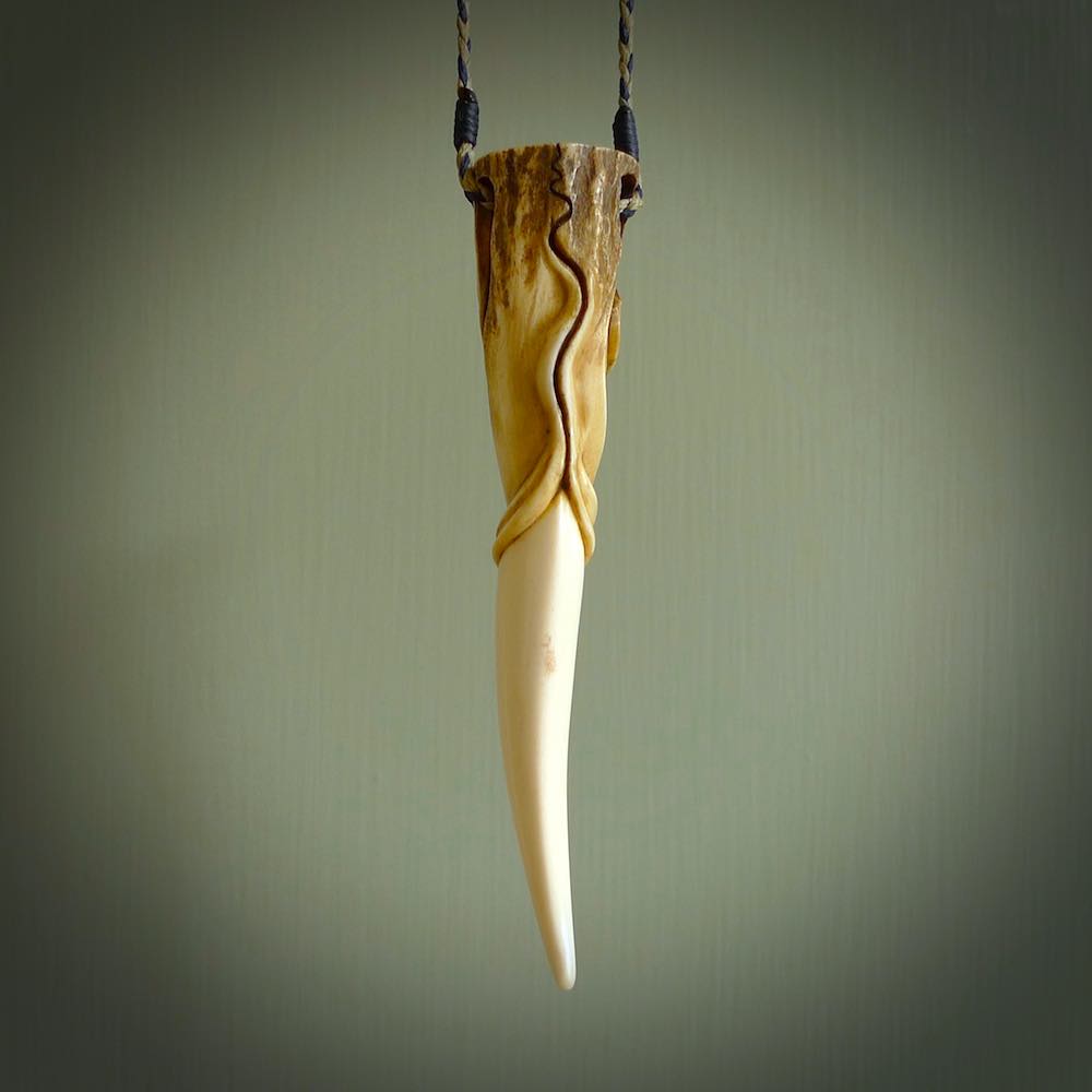 Hand carved Deer Antler Spring of Life pendant with Paua shell cap. This is a longish piece carved from the tip of a deer antler tine. The skin of the antler has been worked into the design so it is an organic design that shows its heritage. Carved for NZ Pacific by Fumio Noguchi.